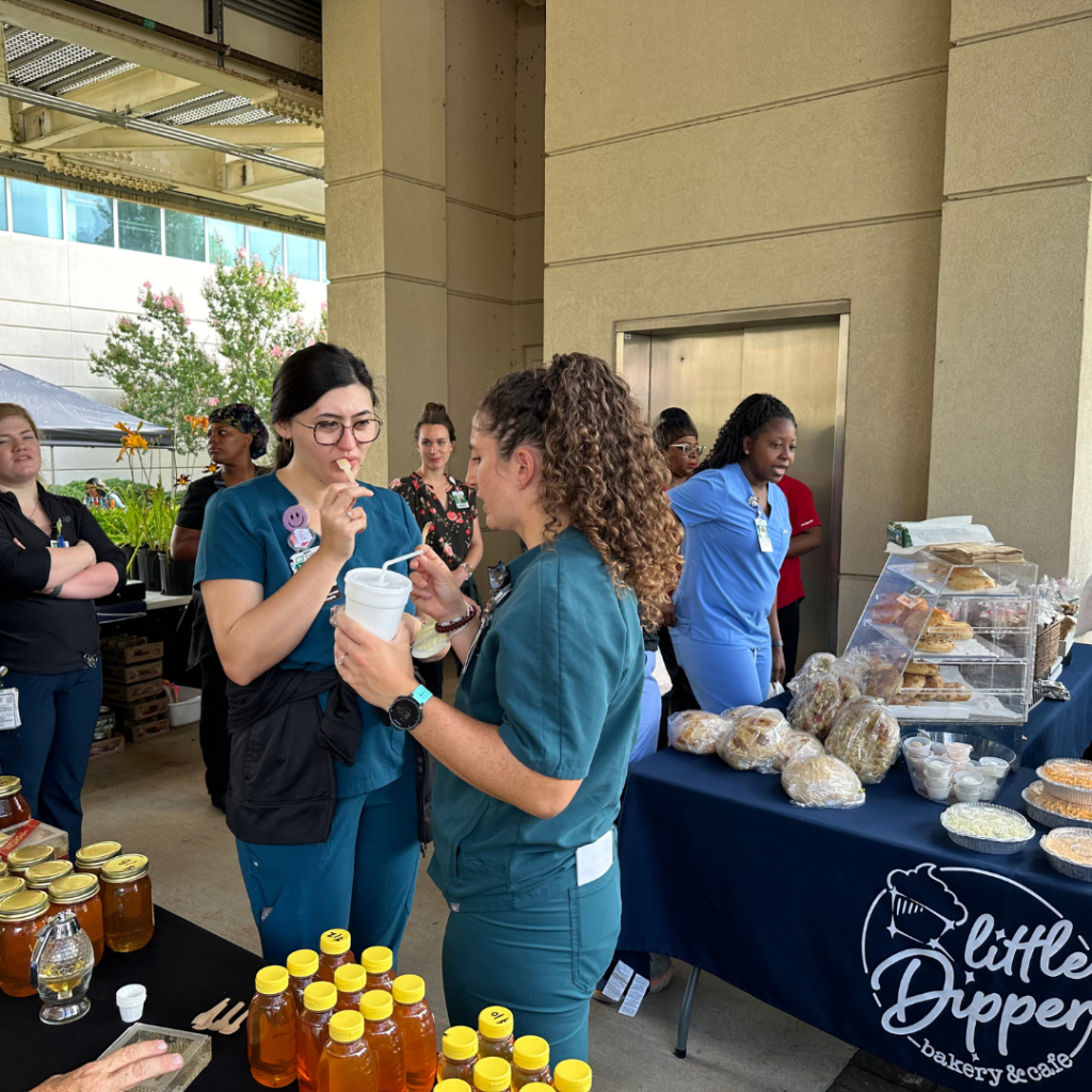 Two women sampling honey at the downtown huntsville farmers market