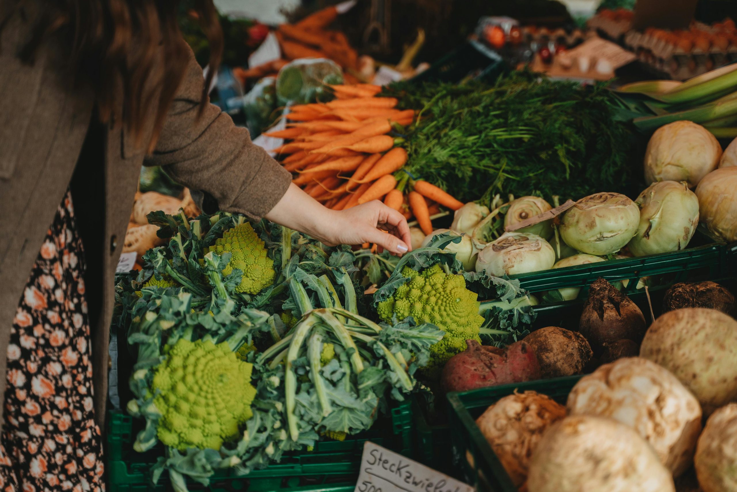 Close up of a person's hand selecting fresh produce from a farmers market