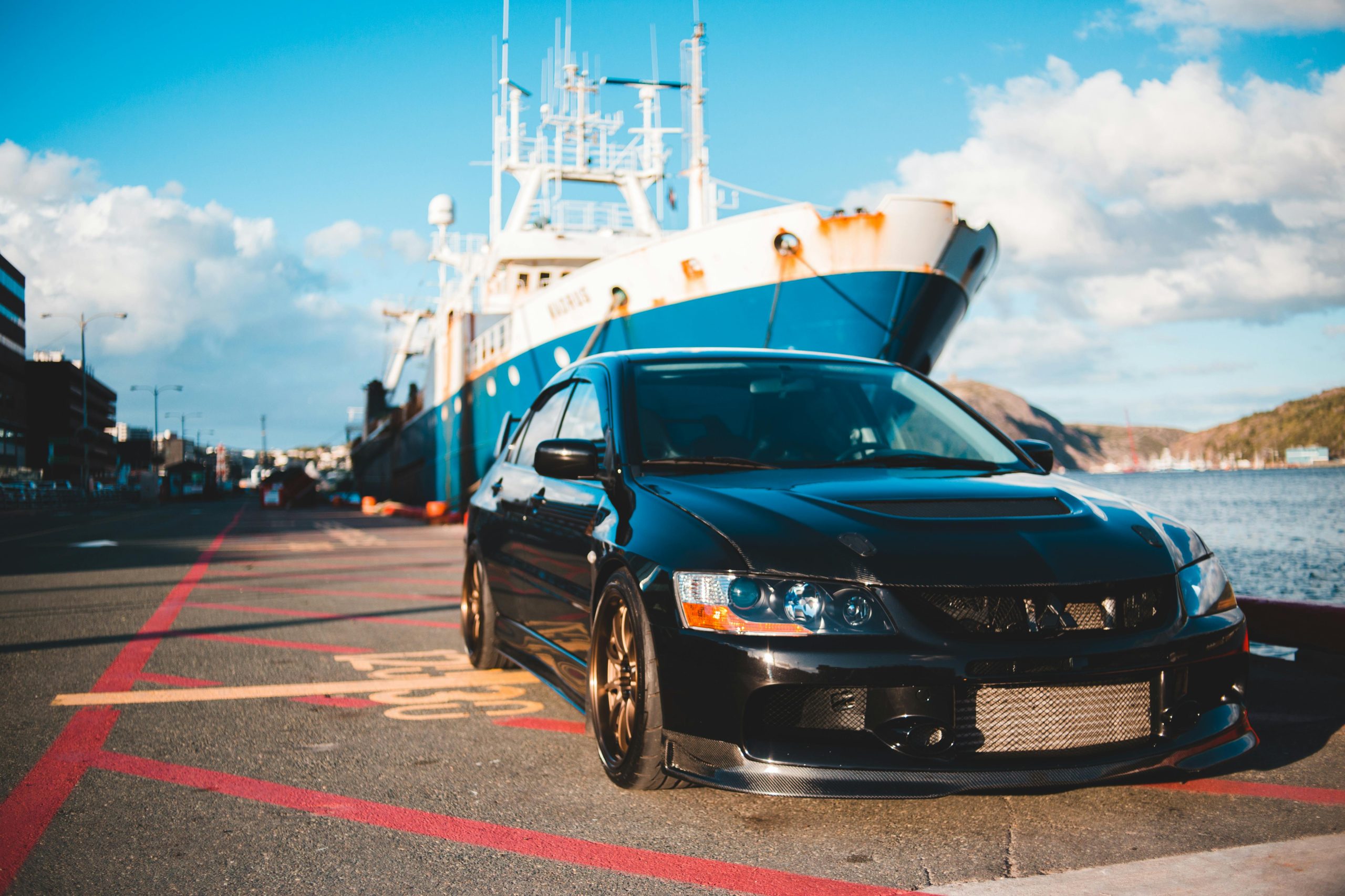 car parked in port beside a ship