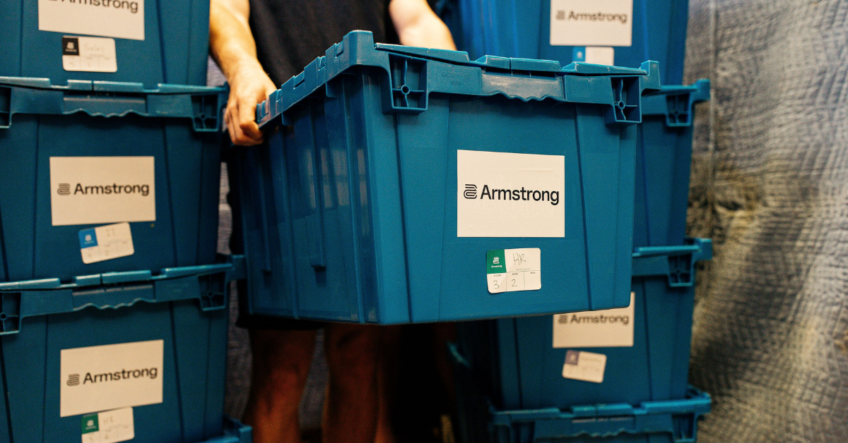 Stacked Armstrong reusable moving boxes with a man carrying one